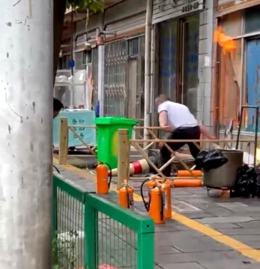 贵州安顺街边店铺液化气罐燃烧 市民挺身而出救险 图为杨俊将煤气罐拖出来。 视频截图